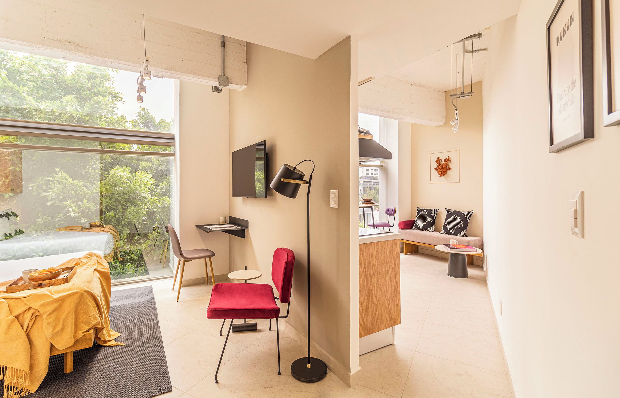 A modern interior with a dining area, a red chair, a small table, and a sofa.