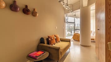 Un interior moderno con un sofá, una mesita con un libro y jarrones decorativos en la pared.