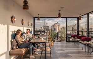 A modern interior with a city view, featuring a seating area with a table, chairs, and a sofa. - Kukun Insurgentes Roma (Mexico City)