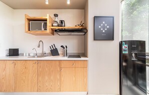 A modern kitchen with a built-in microwave, a stove, and a water dispenser on the refrigerator. - Kukun Insurgentes Roma (Mexico City)