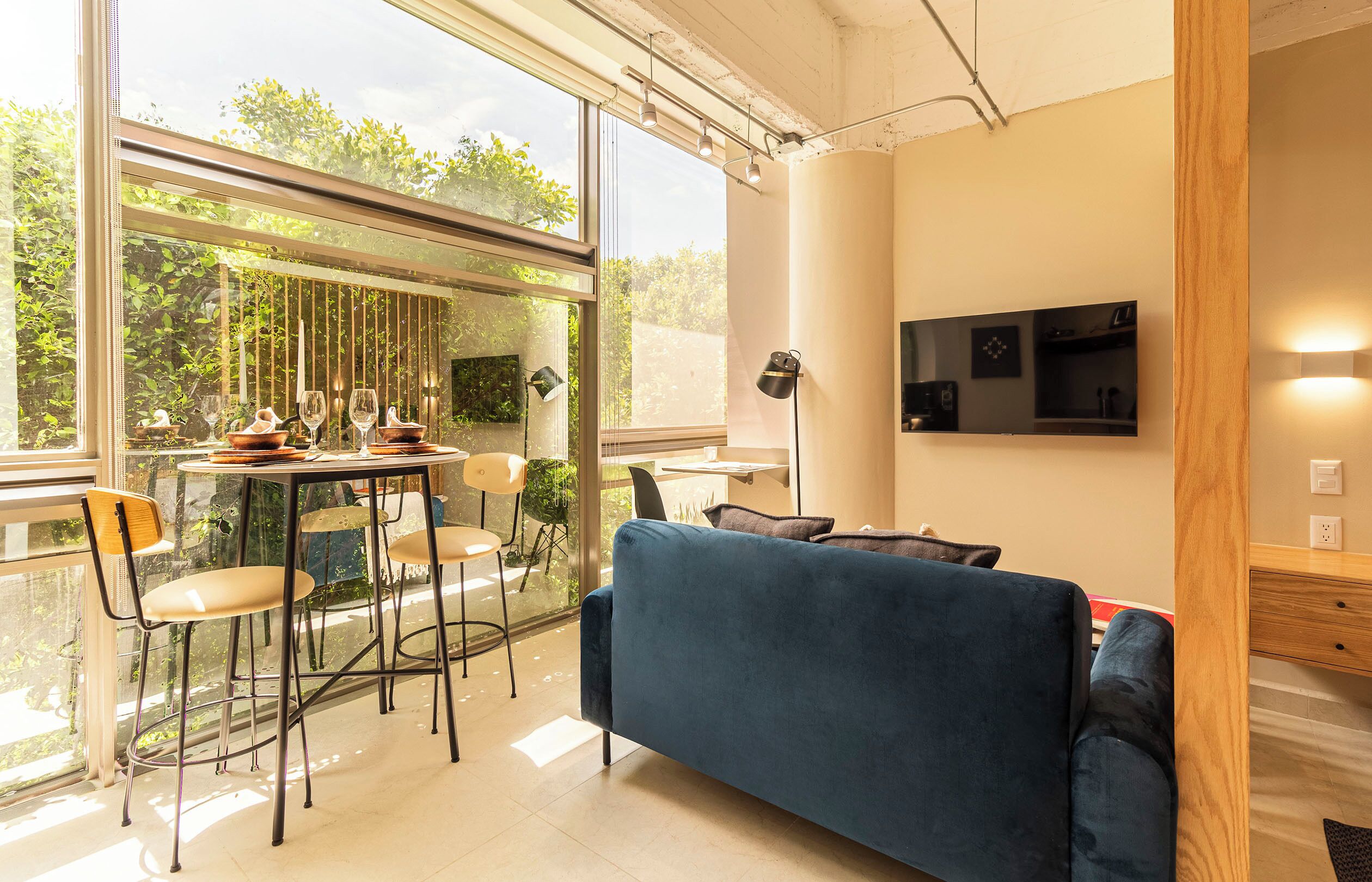 A modern living space with a dining area, a sofa, and a TV mounted on the wall.