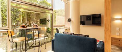 A modern living space with a dining area, a sofa, and a TV mounted on the wall.