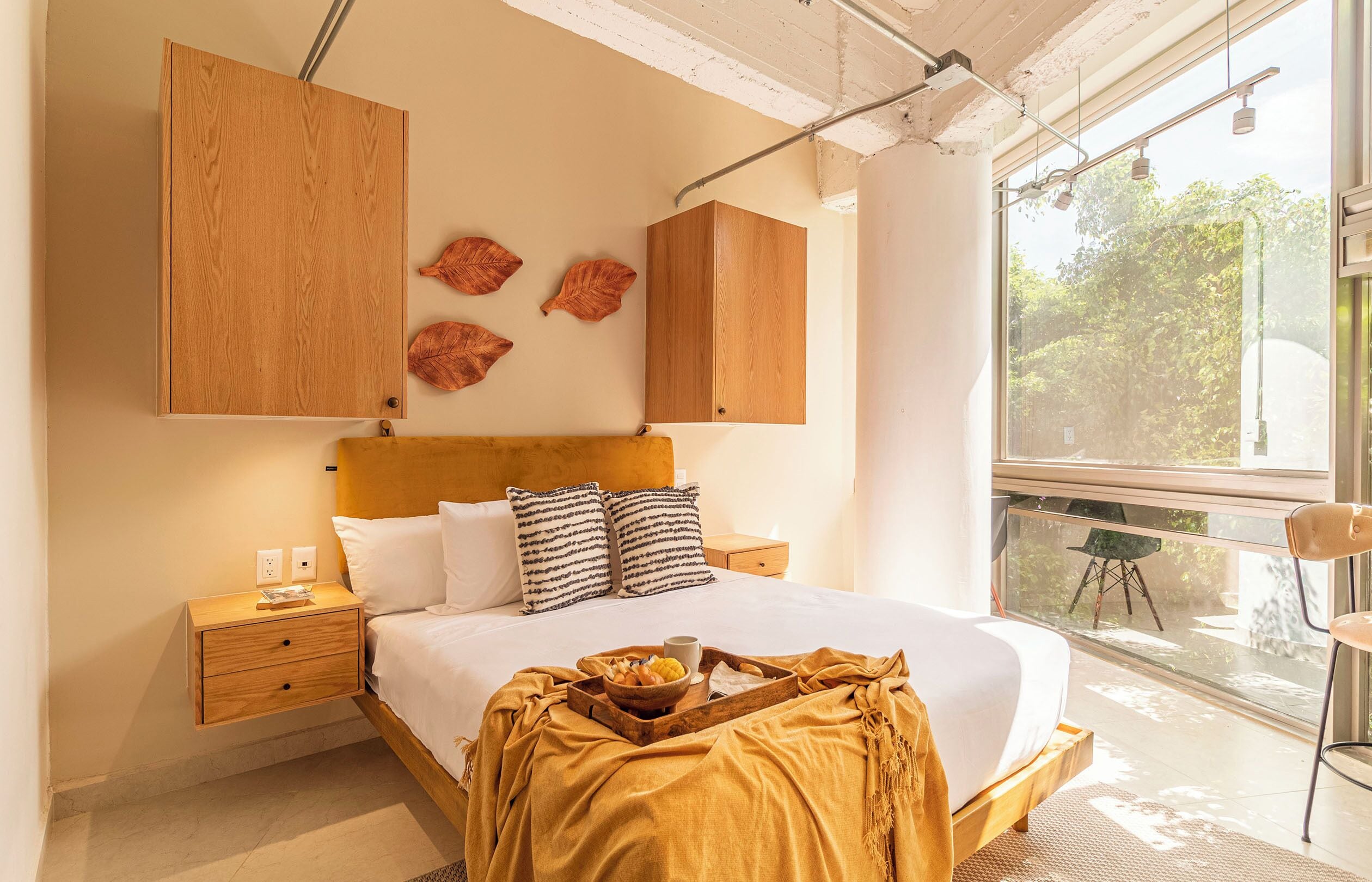Un dormitorio con cama, cabecera de madera, mesitas de noche y ventana con vistas a zonas verdes.