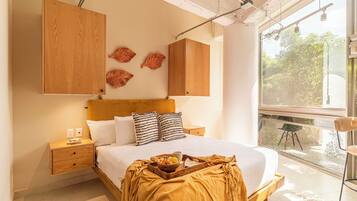 Un dormitorio con cama, cabecera de madera, mesitas de noche y ventana con vistas a zonas verdes.