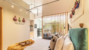 A modern hotel room with a bed, a wooden side table, a decorative wall, and a view through a glass partition. - Kukun Insurgentes Roma (Mexico City)