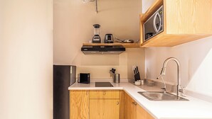 A compact kitchen with a microwave, coffee maker, and a blender on the countertop. - Kukun Insurgentes Roma (Mexico City)