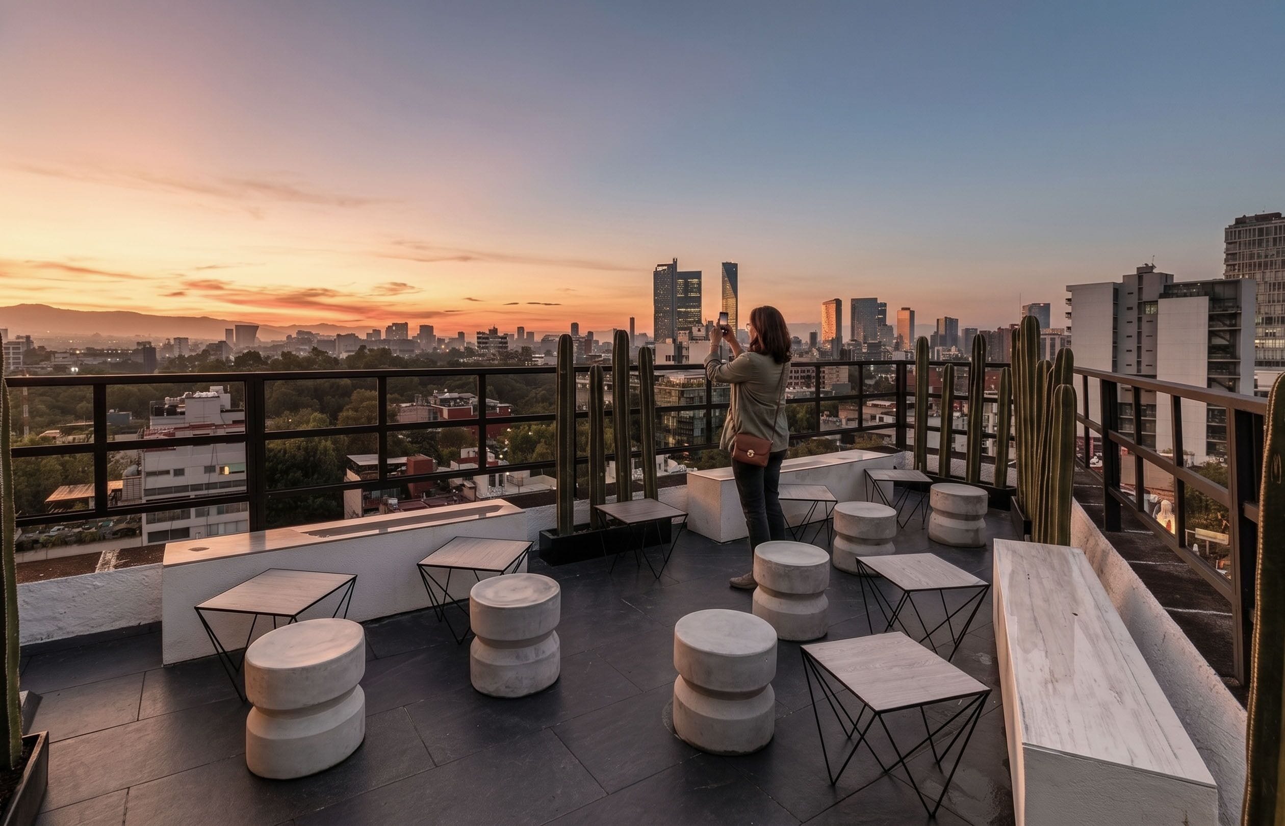 Une terrasse sur le toit, aménagée avec des sièges, offrant une vue sur le panorama urbain au coucher du soleil.