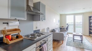A modern kitchen with a gas stove, wooden storage, and a view to a balcony. - Modern 1BD Flat - 5 min walk to Battersea Park! (London)