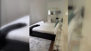 Et hotelværelse med en seng, et natbord, en lampe og et spejl.