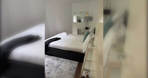 A hotel room with a bed, a bedside table, a lamp, and a mirror. - Fantastically Located 1BD Flat in Islington (London)