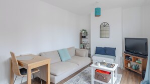En moderne stue med en sofa, et spisebord, et fjernsyn og et bogreol.