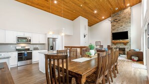 A spacious kitchen with white cabinets, stainless steel appliances, and a wooden dining table with chairs.