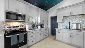 Une cuisine moderne avec des meubles blancs, une cuisinière noire et un four à micro-ondes.