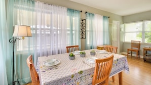Un comedor con una mesa dispuesta para cuatro personas, rodeada de sillas, una lámpara y plantas decorativas sobre la mesa.