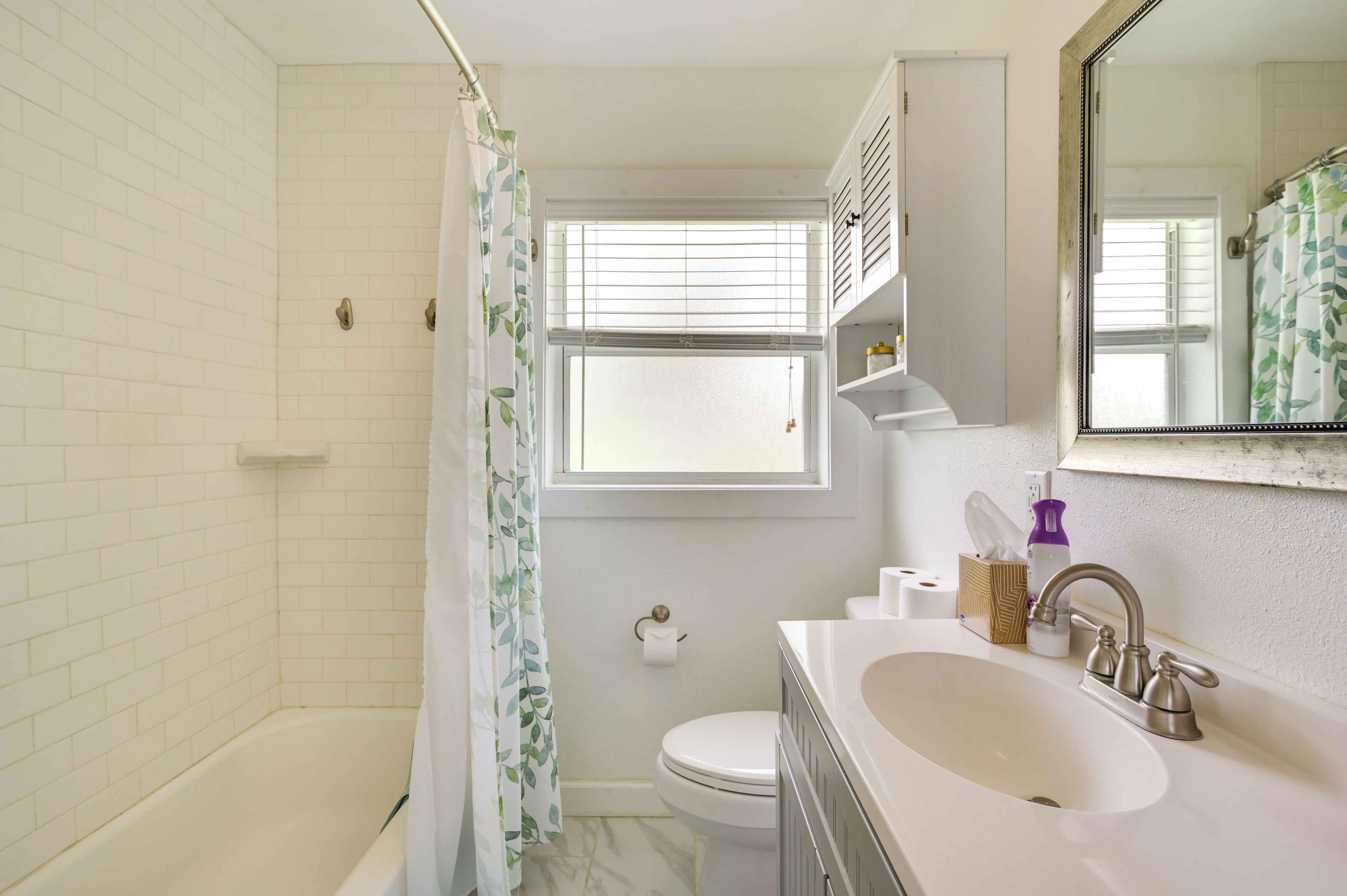 A bathroom with a bathtub, toilet, sink, and a window with blinds.
