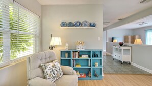 Una sala de estar con un sofá, una estantería azul y platos decorativos en la pared.