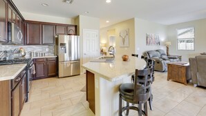 A spacious kitchen with modern appliances, a central island, and a dining area with bar stools. - Resort Pools + More Perks! 55 + Goodyear Escape (Goodyear)