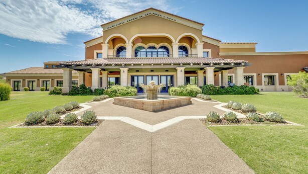 A large building with a central courtyard, a fountain, and a well-maintained lawn. - Resort Pools + More Perks! 55 + Goodyear Escape (Goodyear)