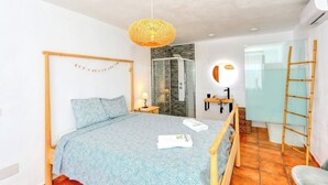 Une chambre moderne avec un lit, une table de chevet, une lampe et un espace douche.