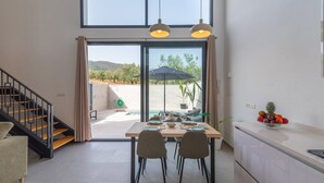 Eine moderne Küche mit Essbereich, großen Fenstern und Blick ins Freie.