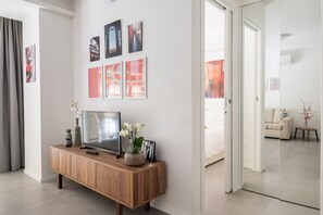 A modern hotel room with a wooden console table, a flat-screen TV, and artwork on the wall.