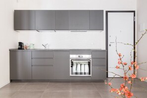 A modern kitchen with grey cabinets, a built-in oven, and a white tiled backsplash.