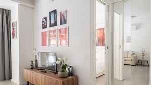 A modern hotel room with a wooden console table, a flat-screen TV, and artwork on the wall. - UR-NEST San Gervasio, charming one-bedroom apartment (Bologna)