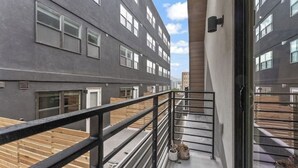 Un edificio moderno con un balcone, ringhiere metalliche e cielo sereno.