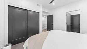 Una camera da letto con un letto, una ventola a soffitto e armadi di colore scuro.