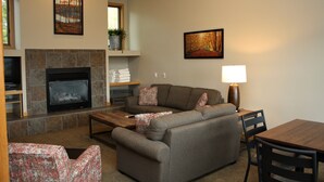 A living room with a fireplace, a sofa, a coffee table, and a lamp. - Deluxe Three Bedroom Condo. AMAZING VIEWS. On bus route. Pet friendly. (Breckenridge)