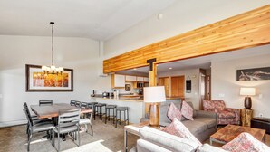 En rummelig opholdsstue med spisebord, sofaer og et køkken i baggrunden.