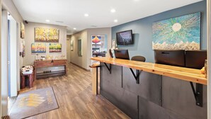 Een receptie met een houten balie, een aan de muur bevestigde televisie en diverse kunstwerken.