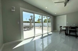 Enjoy a spacious interior with a sliding glass door leading to an outdoor area, a dining table, and a ceiling fan.
