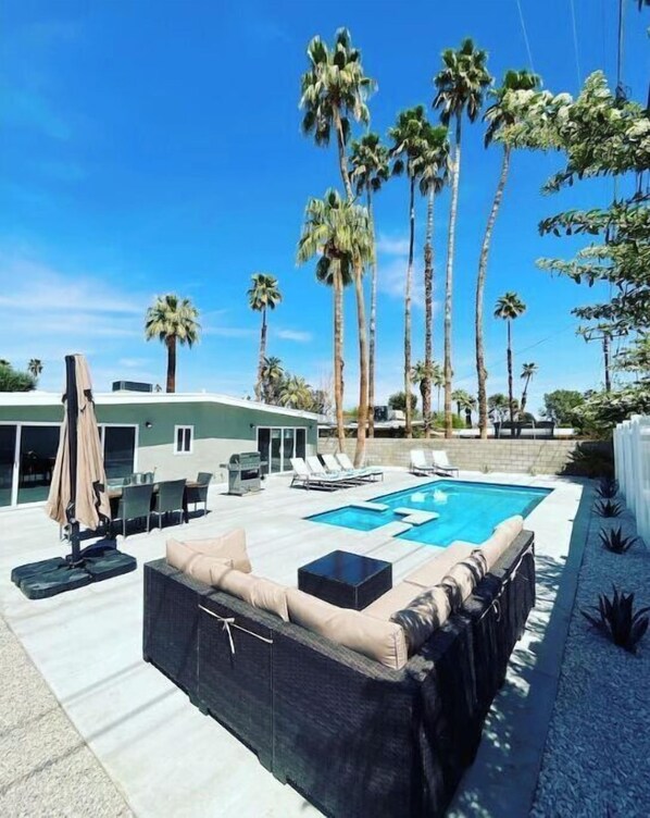 Relax by the rectangular pool surrounded by palm trees and lounge chairs.