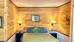 Una stanza accogliente in legno con un letto, due comodini e lampade a parete.