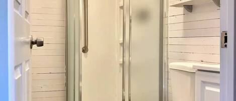Un baño con ducha de vidrio, inodoro y lavamanos.