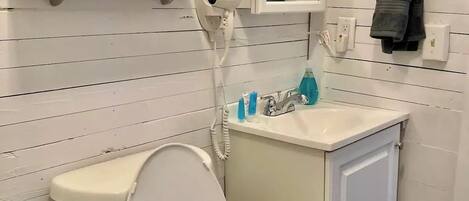 A bathroom with a toilet, sink, and a framed picture on the wall.