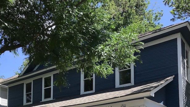 A two-story house with a porch, white railings, and a number "1201" on the front.
