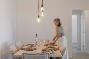 A dining area with a wooden table set for a meal, surrounded by chairs. There are hanging light fixtures above the table. - Funchal, with pool - Uptown 13 apartment (Funchal)