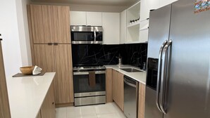 Eine moderne Küche mit Edelstahlgeräten, Holzschränken und einer Marmor-Spritzschutzwand.