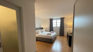 Ein modernes Hotelzimmer mit einem großen Bett, einem Schreibtisch und einem Fenster mit Vorhängen.