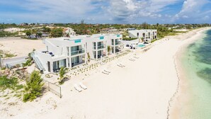 Un resort frente al mar con arquitectura moderna, piscina y servicios en la playa.