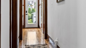 A hallway with wooden flooring, a patterned rug, a door leading outside, and a mirror on the wall. - Newly Renovated Gem in Melrose  - Pet Friendly (Albany)