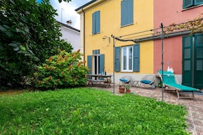 A courtyard with a table, chairs, and a lounge chair. - Wonderful villa, divided over two floors, with garden. Independent entrance.Basement with laundry area.It comfortably accommodates 6 guests in 100 m2 of space with three bedrooms and two bathrooms.LIVING AREA: living room with double sofa bed, 32 TV, si (Parma)