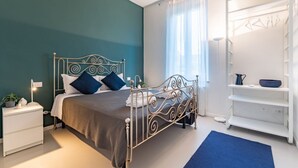 A modern bedroom with a metal bed frame, a bedside table, a nightstand, a blue rug, a white wardrobe, and a window with sheer curtains. - Wonderful villa, divided over two floors, with garden. Independent entrance.Basement with laundry area.It comfortably accommodates 6 guests in 100 m2 of space with three bedrooms and two bathrooms.LIVING AREA: living room with double sofa bed, 32 TV, si (Parma)
