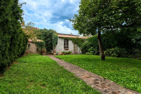 A stone pathway leading to a rustic building with ivy-covered walls and a traditional tiled roof.