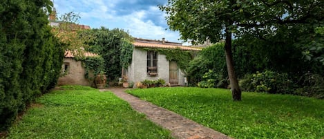 A stone pathway leading to a rustic building with ivy-covered walls and a traditional tiled roof.