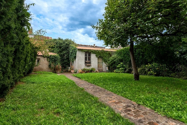 A stone pathway leading to a rustic building with ivy-covered walls and a traditional tiled roof. - Wonderful villa, divided over two floors, with garden. Independent entrance.Basement with laundry area.It comfortably accommodates 6 guests in 100 m2 of space with three bedrooms and two bathrooms.LIVING AREA: living room with double sofa bed, 32 TV, si (Parma)