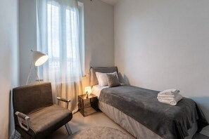 Ein Schlafzimmer mit Bett, Stuhl, Nachttisch und Lampe.