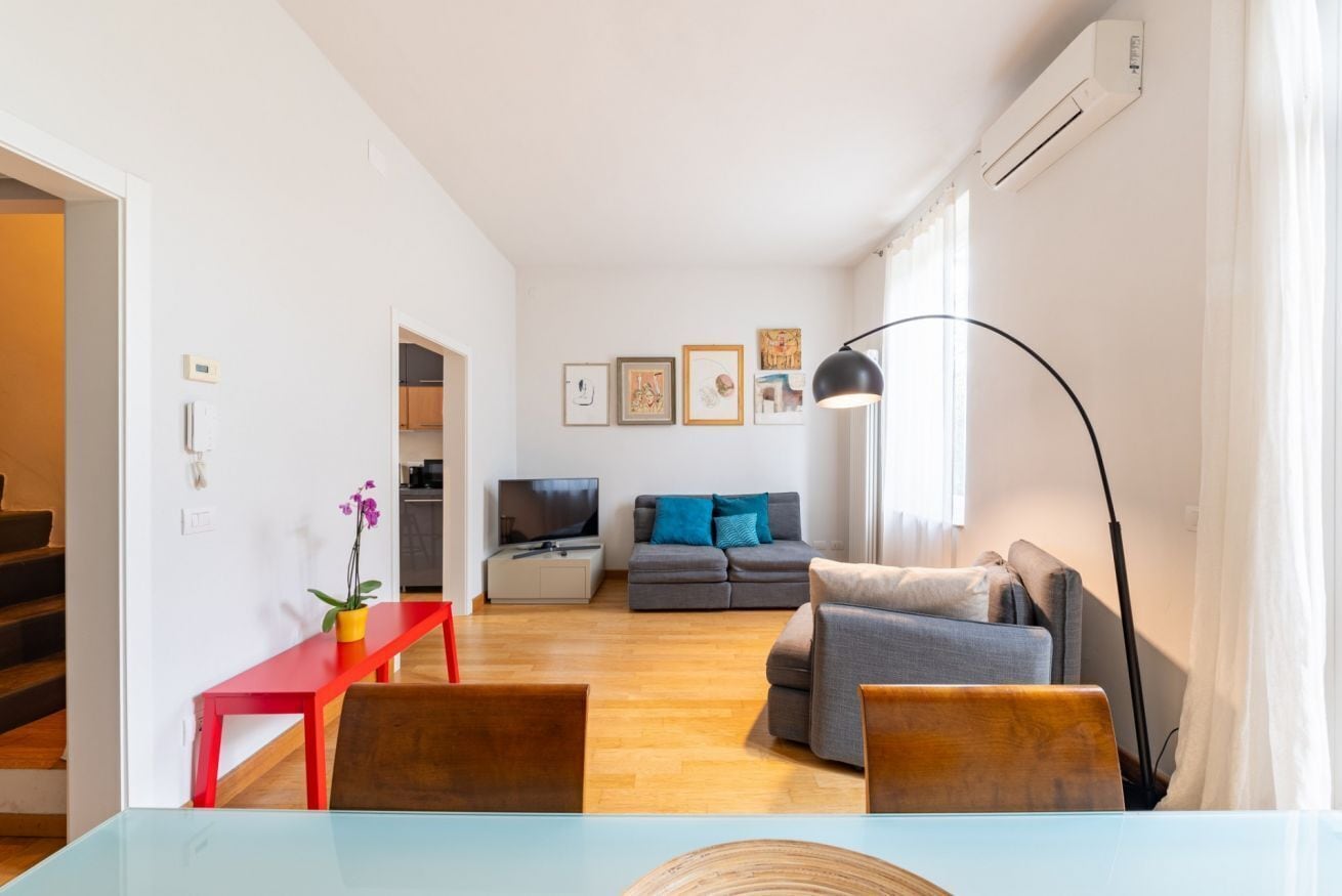 A modern living room with a sofa, a TV, and a red bench.